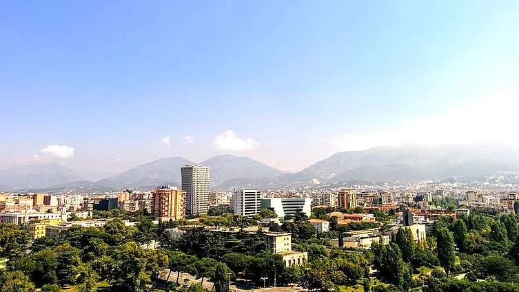 Aerial view of Tirana, Albania's capital, with mountain backdrop and clear skies.