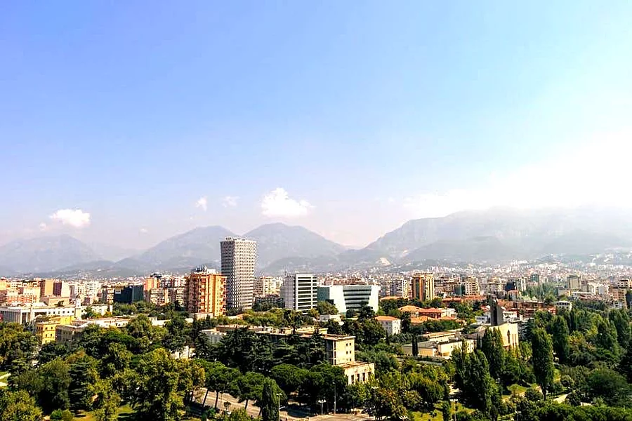 Pamje ajrore e Tiranës, kryeqytetit të Shqipërisë, me malet në sfond dhe qiell të kthjellët.